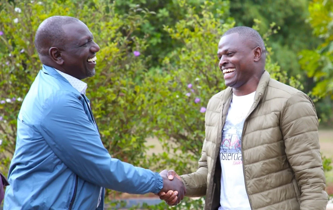 President William Ruto shaking hands with Kiharu MP Ndindi Nyoro smiling outdoors