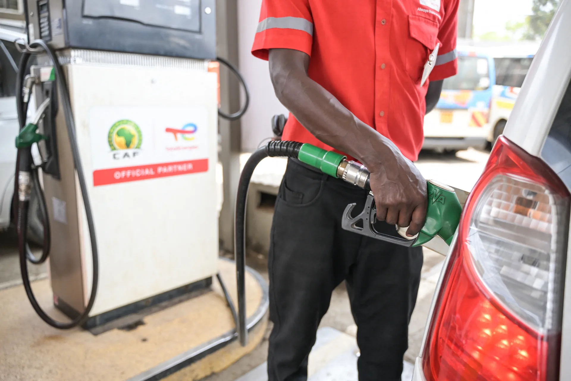 Fuel attendant in red shirt fuelling a car at a TotalEnergies petrol station in Kenya